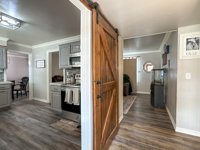 kitchen featuring dark wood finished floors, gray cabinets, a barn door, appliances with stainless steel finishes, and ornamental molding