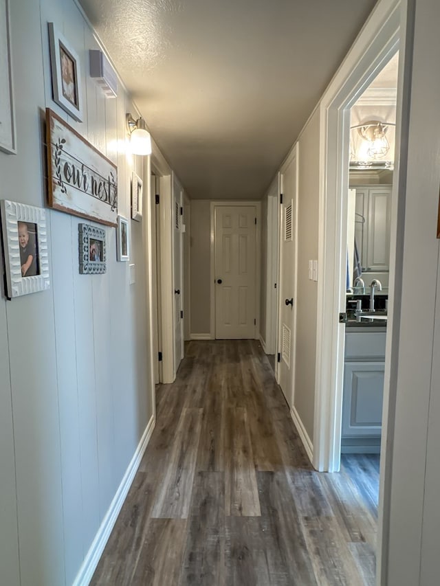 corridor with a sink, baseboards, and dark wood-style flooring