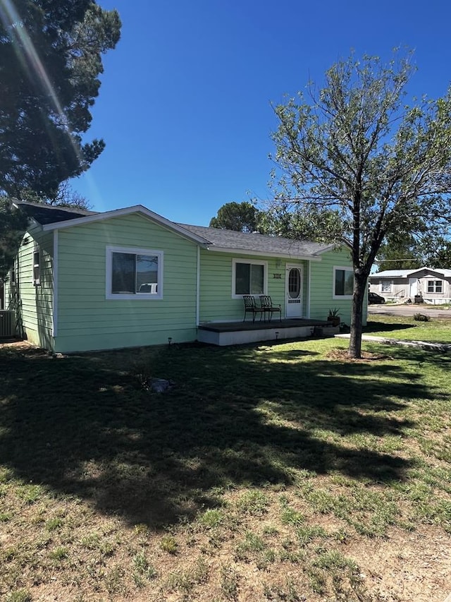 single story home featuring cooling unit and a front lawn