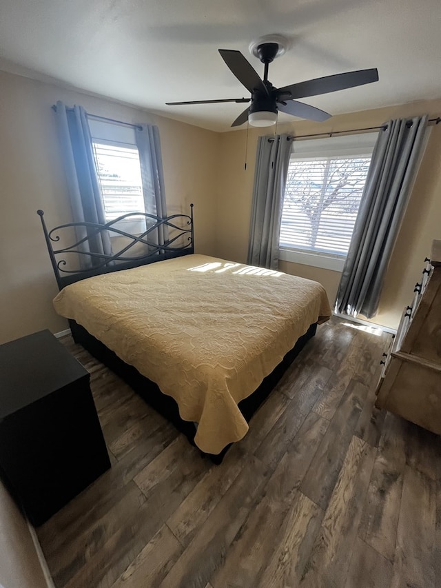 bedroom featuring ceiling fan, dark hardwood / wood-style flooring, and multiple windows