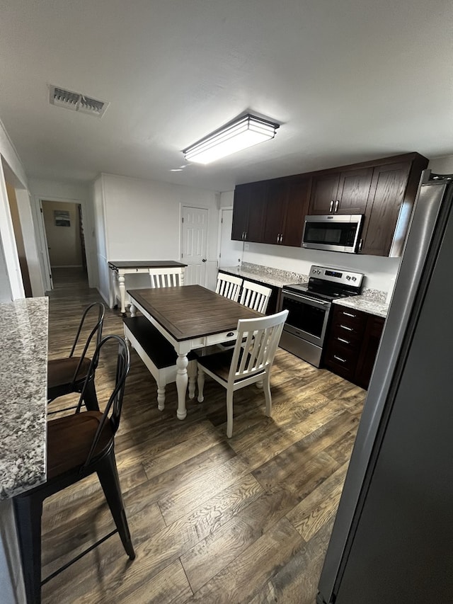 kitchen with dark wood-type flooring, appliances with stainless steel finishes, and dark brown cabinets