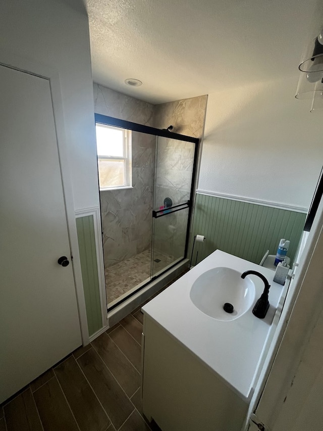 bathroom featuring an enclosed shower, a textured ceiling, and vanity