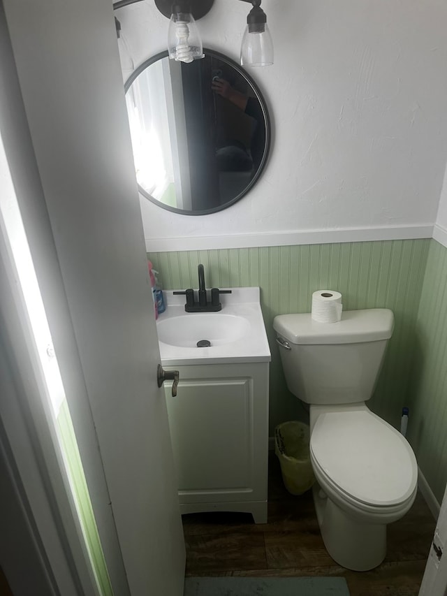 bathroom with hardwood / wood-style floors, wood walls, vanity, and toilet