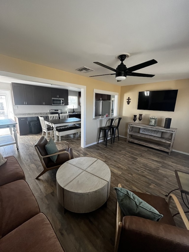 living room featuring dark wood-type flooring, ceiling fan, and sink