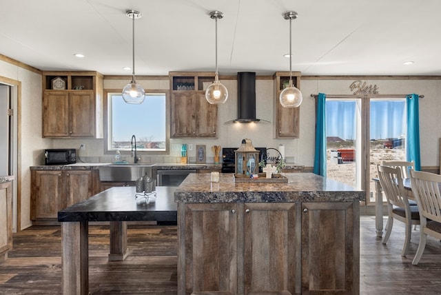 kitchen featuring a sink, wall chimney exhaust hood, a kitchen island, and decorative light fixtures