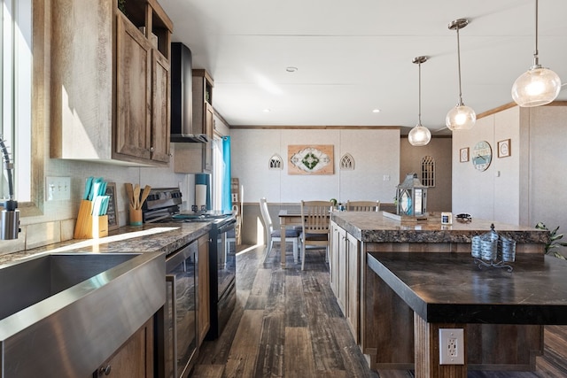 kitchen with wall chimney exhaust hood, electric range, dark countertops, and a kitchen island