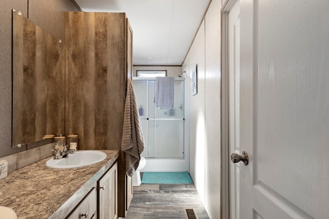 full bathroom featuring shower / bath combination with glass door, visible vents, wood finished floors, and vanity