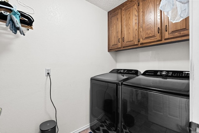 laundry room featuring cabinets, a textured ceiling, and washing machine and clothes dryer