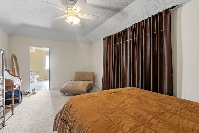 carpeted bedroom with ensuite bathroom, ceiling fan, a textured ceiling, and a tray ceiling