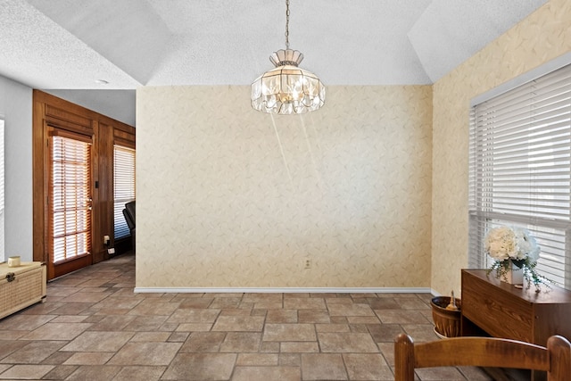 dining room with a chandelier, vaulted ceiling, and a textured ceiling