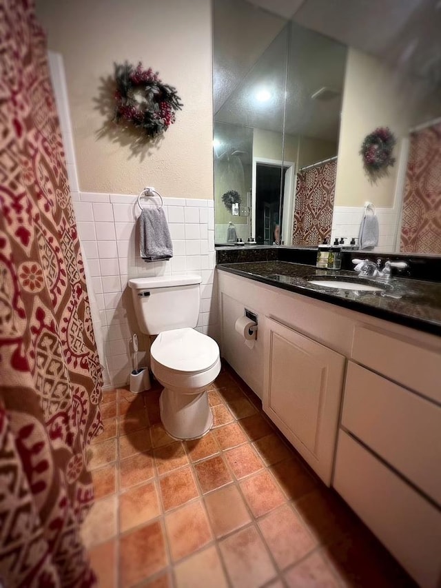 bathroom featuring tile patterned floors, vanity, toilet, and tile walls