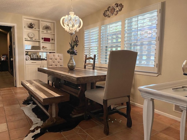 dining room featuring tile patterned flooring, a textured ceiling, and an inviting chandelier