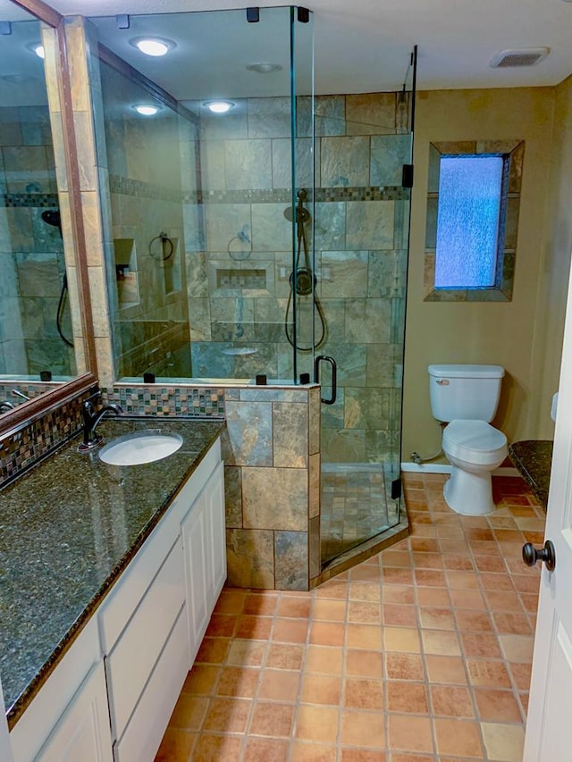 bathroom featuring tile patterned floors, vanity, toilet, and a shower with door