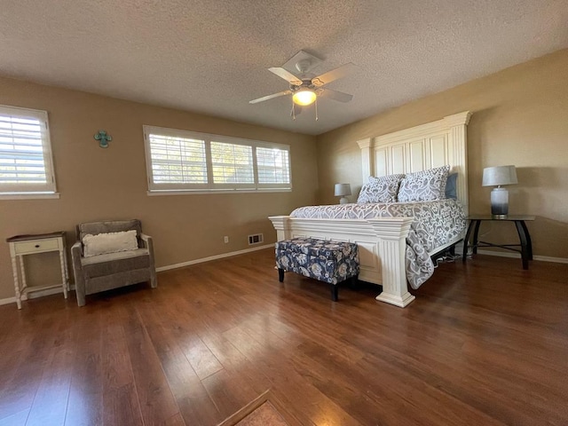 bedroom featuring multiple windows, ceiling fan, dark wood-type flooring, and a textured ceiling