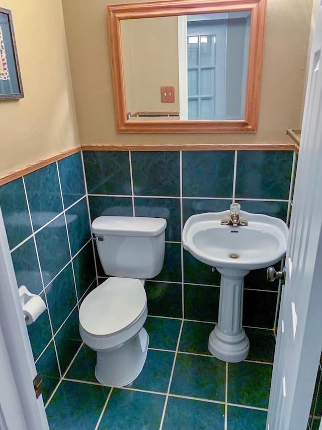 bathroom featuring tile patterned flooring, toilet, and tile walls