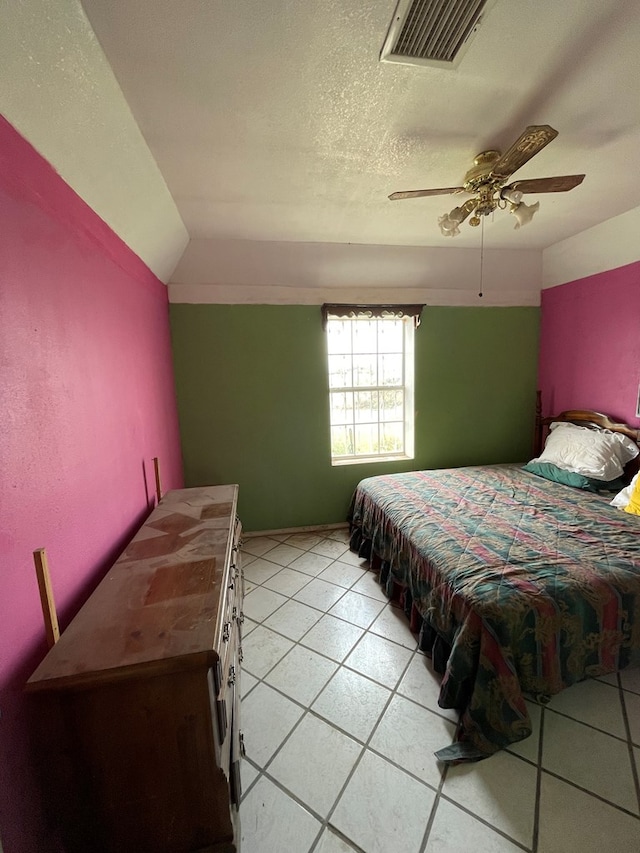 tiled bedroom with ceiling fan and a textured ceiling