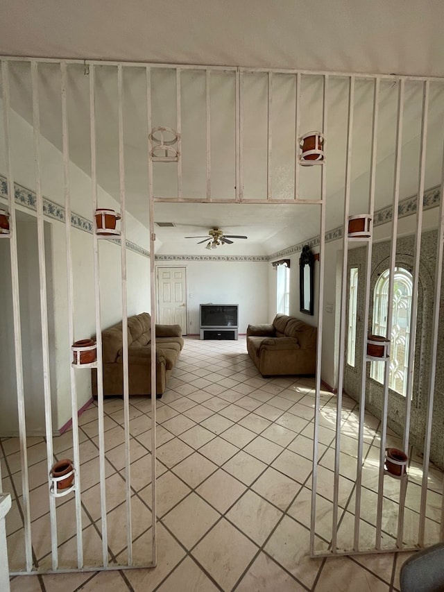 unfurnished living room with tile patterned flooring, ceiling fan, a fireplace, and a wealth of natural light