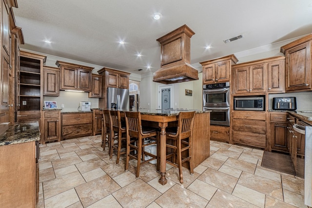 kitchen with a kitchen breakfast bar, dark stone countertops, a kitchen island, and appliances with stainless steel finishes