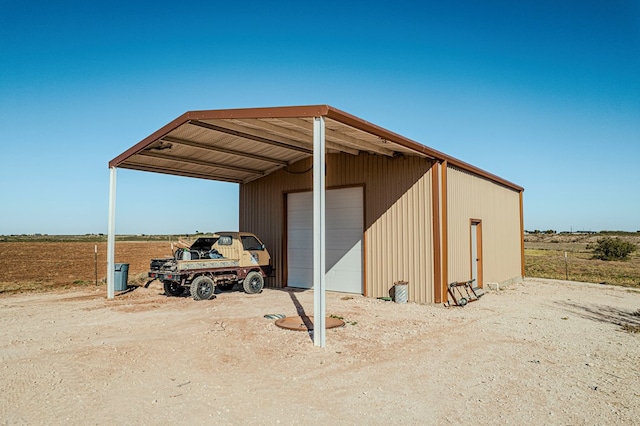 view of outdoor structure with a carport, a rural view, and a garage