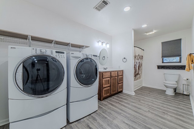 washroom with washer and clothes dryer and light hardwood / wood-style flooring