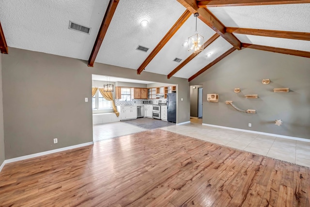 unfurnished living room featuring vaulted ceiling with beams, a textured ceiling, an inviting chandelier, and light hardwood / wood-style flooring