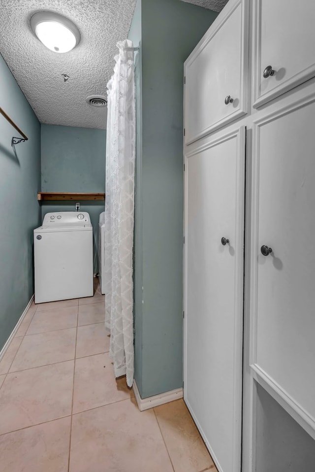 bathroom with tile patterned flooring, washer and dryer, and a textured ceiling