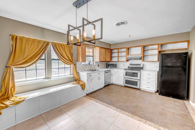 kitchen featuring a wealth of natural light, hanging light fixtures, exhaust hood, and appliances with stainless steel finishes