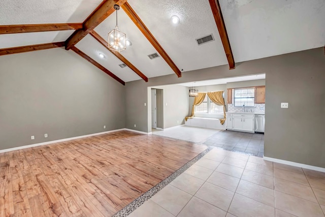 unfurnished living room featuring a textured ceiling, lofted ceiling with beams, light hardwood / wood-style flooring, and a notable chandelier