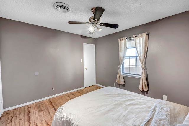 bedroom with hardwood / wood-style floors, ceiling fan, and a textured ceiling