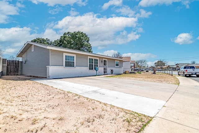 single story home featuring brick siding, concrete driveway, and fence