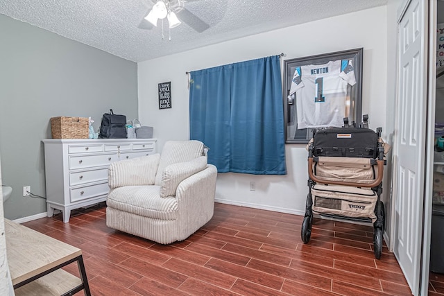 sitting room with wood finish floors, baseboards, a textured ceiling, and ceiling fan