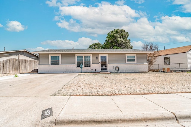 ranch-style house with brick siding, driveway, and fence