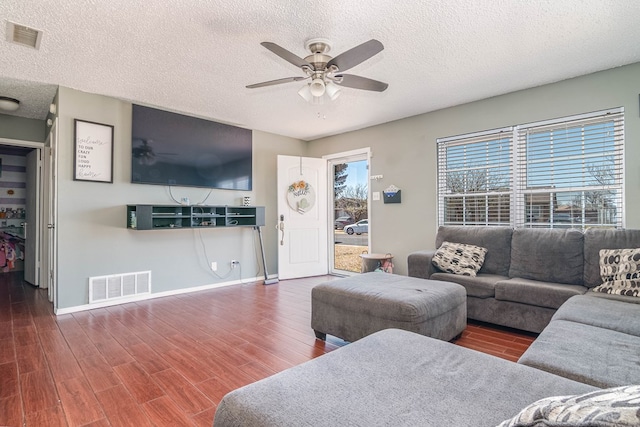 living area with wood finished floors, a ceiling fan, visible vents, and baseboards