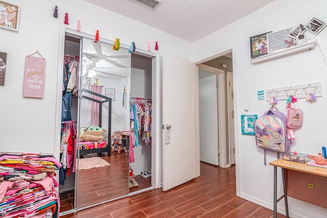 bedroom with a closet, a textured ceiling, visible vents, and wood tiled floor