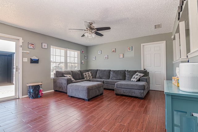 living room with dark wood finished floors, a textured ceiling, visible vents, and ceiling fan