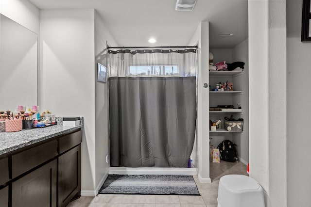 bathroom featuring walk in shower, vanity, and tile patterned flooring