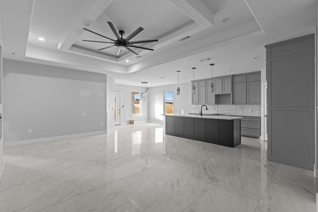 kitchen featuring a sink, gray cabinets, open floor plan, and a raised ceiling