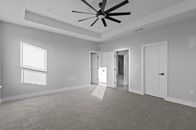 unfurnished bedroom featuring a tray ceiling, carpet flooring, and baseboards