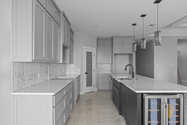 kitchen with beverage cooler, backsplash, a sink, and gray cabinetry