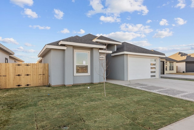 prairie-style home featuring stucco siding, concrete driveway, an attached garage, fence, and a front lawn