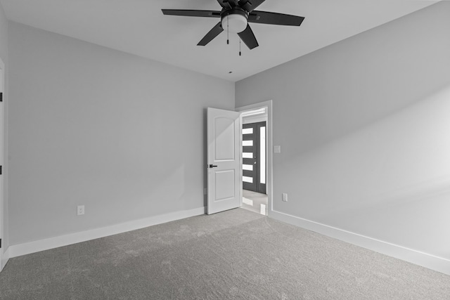 carpeted spare room featuring baseboards and a ceiling fan