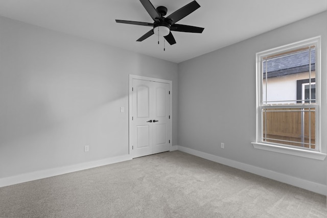 carpeted spare room with a ceiling fan and baseboards