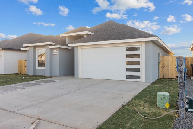 view of front of property with concrete driveway, roof with shingles, an attached garage, fence, and stucco siding