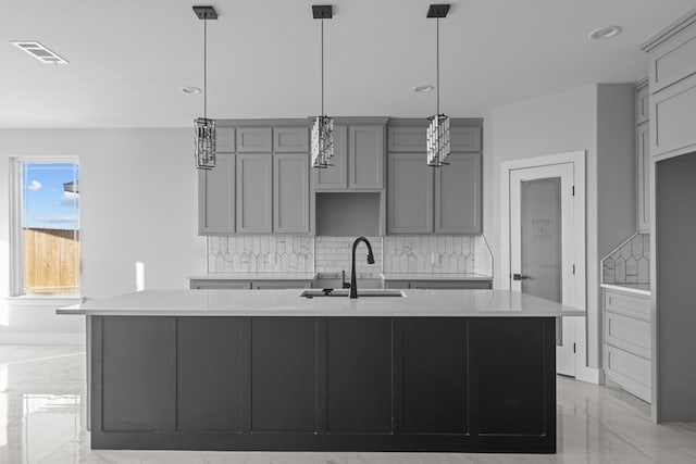 kitchen with gray cabinetry, a sink, visible vents, marble finish floor, and a center island with sink