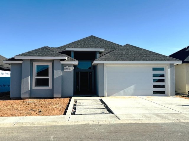 view of front of property with a garage, concrete driveway, a shingled roof, and stucco siding