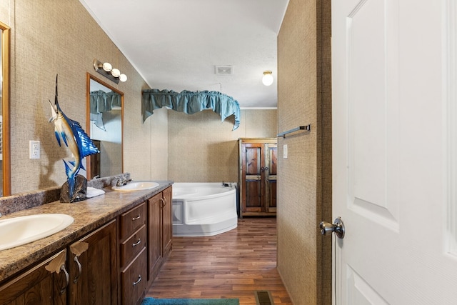 full bathroom with double vanity, visible vents, a sink, wood finished floors, and a bath