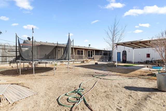 rear view of house with a trampoline and fence