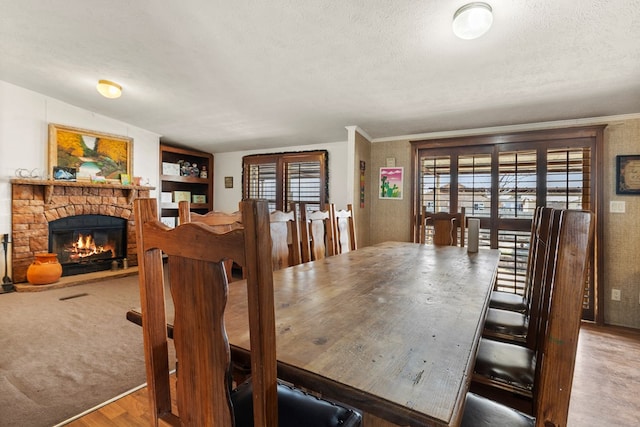 dining space featuring a textured ceiling, ornamental molding, a wealth of natural light, and a stone fireplace