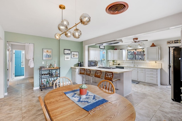 tiled dining space with ceiling fan and sink