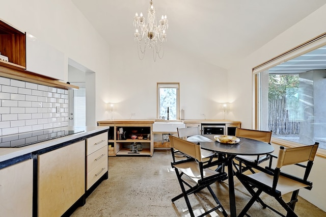 dining area featuring plenty of natural light, vaulted ceiling, sink, and a chandelier